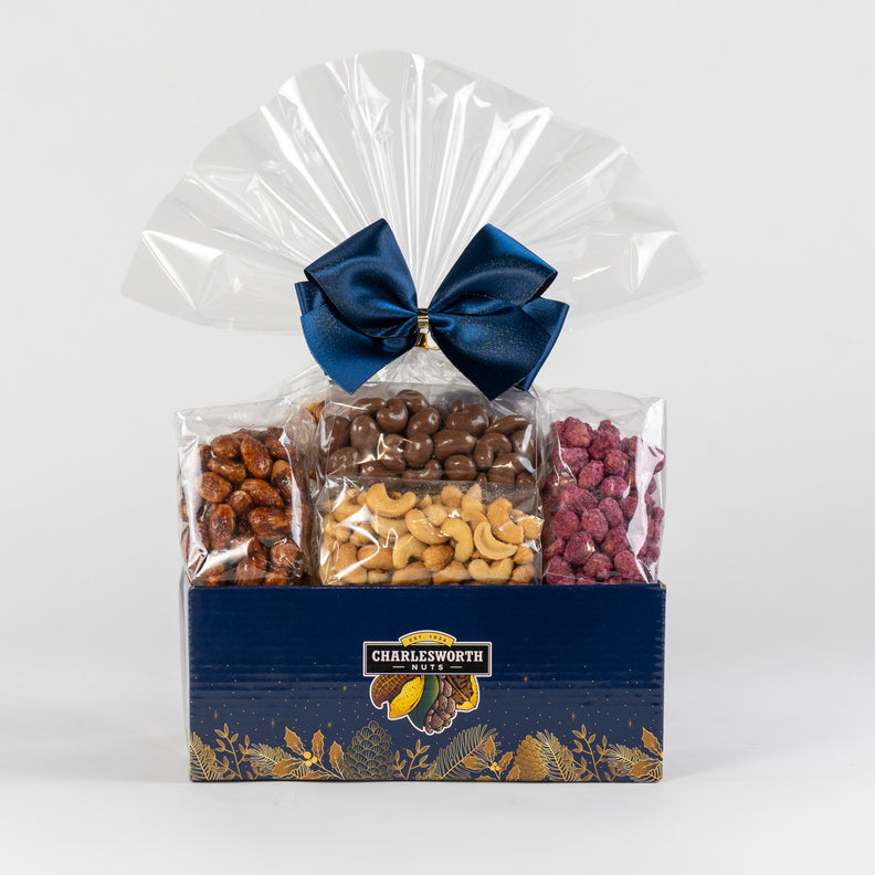 Christmas Gift Basket beautifully wrapped in cellophane and tied with blue bow filled with chocolates and nuts.